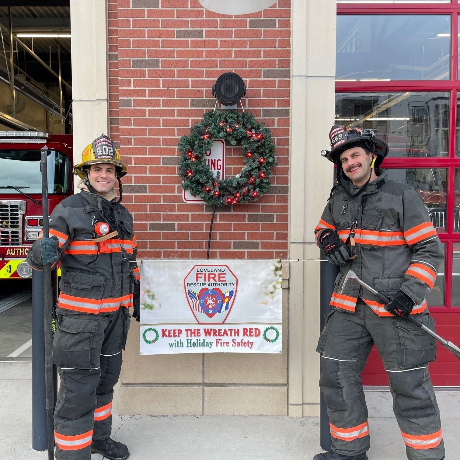Firefighters standing next to a wreath with red lightbulbs